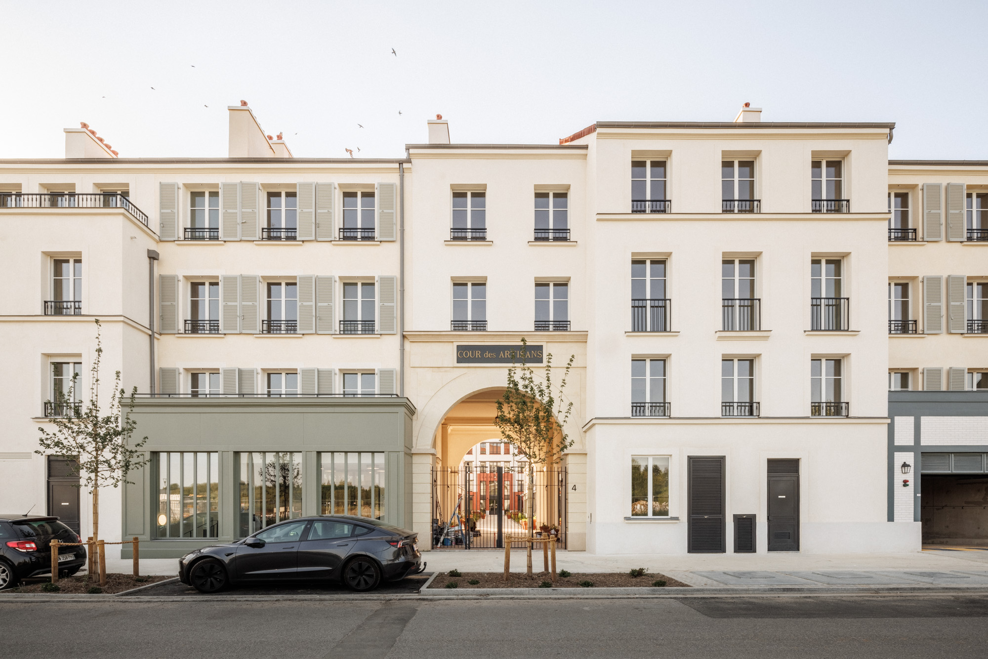Vue du projet de logements collectifs la cour des artisans par Cussac Architectes et Associés (CA+A) à Serris depuis la rue, avec une façade séquencée et proche double hauteur laissant percevoir l'intérieur de la cour.